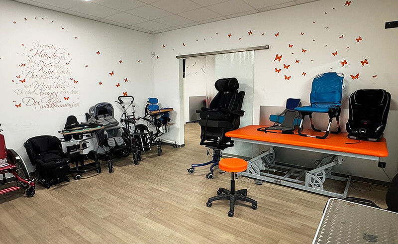 Therapieraum für Kinderrehabilitation mit verschiedenen Reha-Hilfsmitteln, Sitzsystemen und Therapiearbeitsplatz